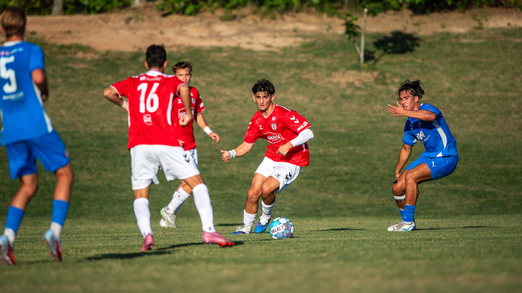 Hickory FC player, Bautista Rossi, in red dribbles the ball during a match against SC Bantams.